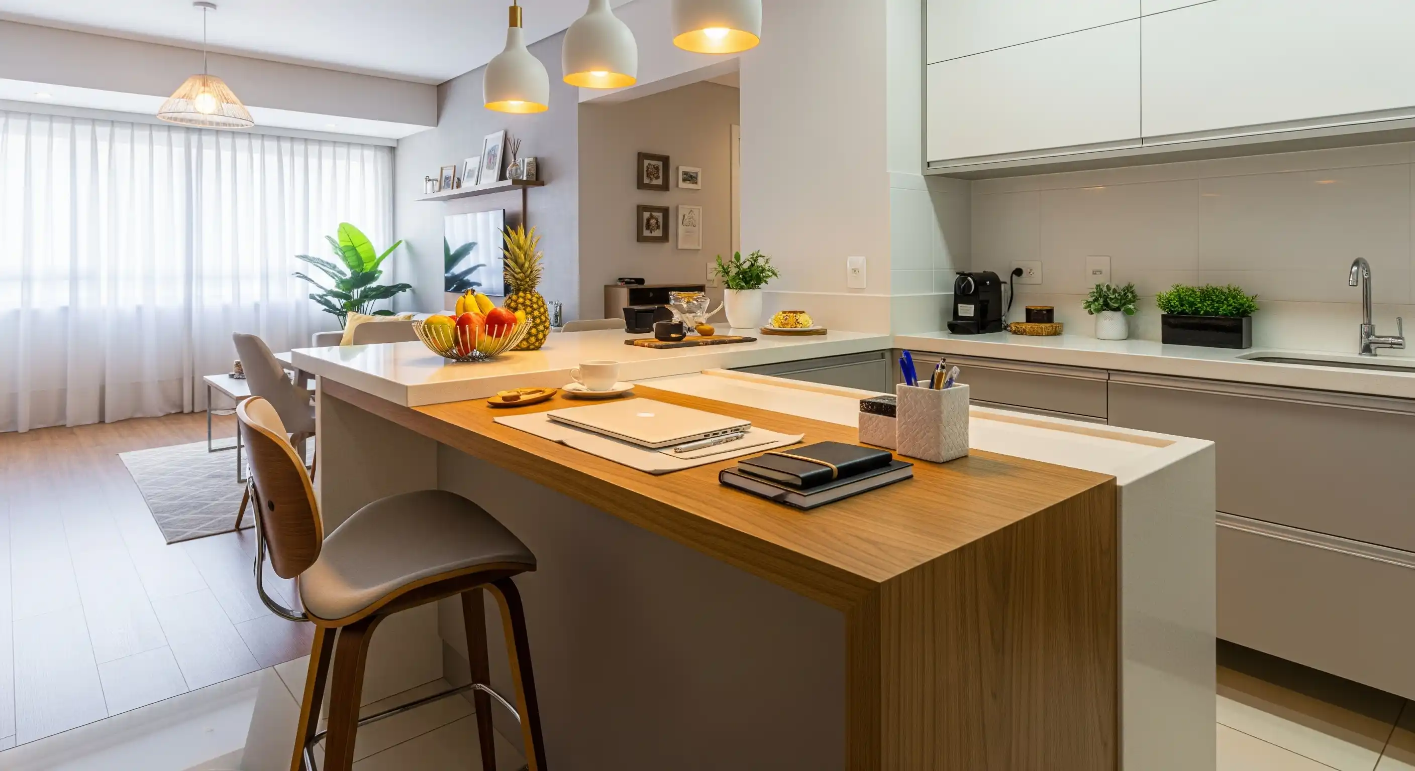 Bancada de cozinha americana que se estende para a sala, com uma parte usada como mesa de trabalho com um banco alto.